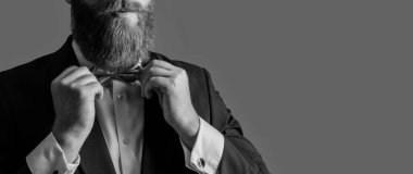 Smokin stüdyosundaki şık papyonunu düzelten sakallı İrlandalı bir adam Grey 'de izole edilmiş. Papyon tarzı. Resmi kıyafet. Resmi giyim, kopyalama alanı.