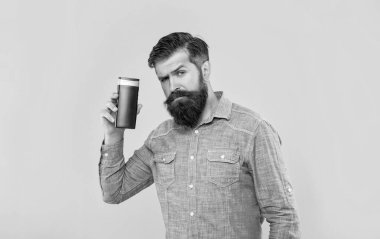 Yakışıklı, vahşi, sakallı adam sarı arka planda saç kremi şişesi tutuyor..