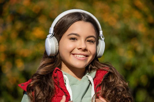喜んで10代の女の子がヘッドフォンを着て音楽を聞く 音楽を聴いている10代の少女の写真です 10代の女の子が屋外で音楽を聴いて 十代の女の子は外で音楽を聞いて — ストック写真