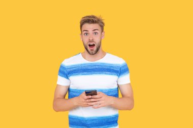 Şok olmuş bir adam mesajlaşmak veya mesaj atmak için telefonunu kullanır. Adam etkili iletişim kurmak için telefonu kullanıyor. Adamın telefon bağlantısı var. Telefonlu adamın dijital iletişimi.