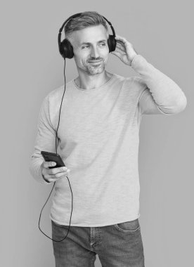 mature man open playlist on mp3 isolated on blue. man open playlist on mp3 at studio. man open playlist on mp3 on background. photo of man open playlist on mp3.