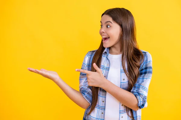 stock image amazed teen girl presenting product to the camera. teen girl presenting product to customers. teen girl presenting product to audience. teen girl presenting her new product on studio background.