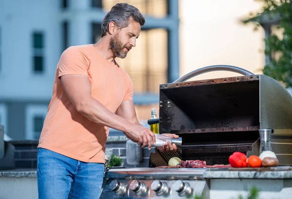 stock image Grilling man cook meat at barbecue. Charcoal grilling expertise. Outdoor man cooking grill and barbecue dishes. Grill mastery in action. Man grilling steaks to perfection on smoky barbecue.