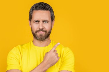 Arka plandaki reklam teklifini işaret eden bir adamın portresi. Stüdyodaki reklam teklifini işaret eden adam. Reklam teklifini işaret eden adamın fotoğrafı. Adam reklam teklifini işaret ediyor.