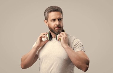 Yakışıklı adam stüdyoda kulaklıkla müzik dinliyor. Modern kulaklıkla müzik dinleyen bir adam. Kulaklıkla müzik dinleyen bir adamın fotoğrafı. Gri kulaklıkla müzik dinleyen adam izole edilmiş.