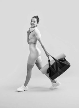 fitness woman smile in sportswear walk with sport bag in studio. fitness woman in workout sportswear isolated on yellow background. fitness and sportswear.