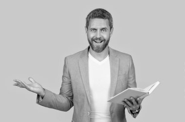 Öğretmenin kitap okurken şok olmuş fotoğrafı. Öğretmen okuma kitabı sarı arka planda izole edilmiş. Ceketli bir kitap okuyan öğretmen. Stüdyoda öğretmen kitabı okurken..