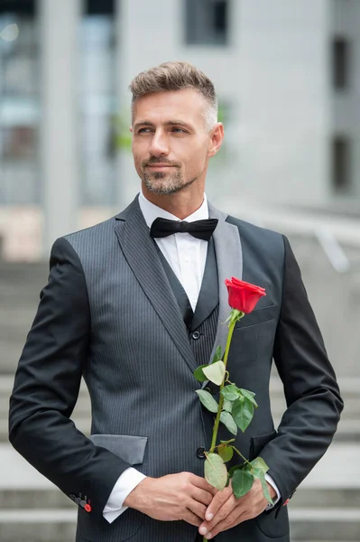 在特殊场合穿正装 带着玫瑰的微笑的男人在特殊的场合 特定场合的室外燕尾服男 — 图库照片