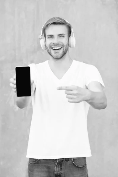 스마트폰으로 제공하는 미소짓는 헤드폰으로 제공하는 남자의 제공하는 밖에서 제공하는 — 스톡 사진
