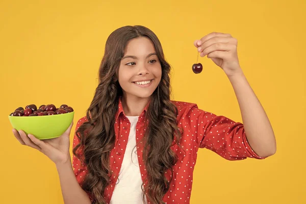 stock image happy teen girl hold cherry bowl on yellow background.