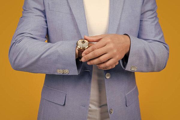 cropped view of man punctuality in studio. photo of handsome man follow punctuality with watch. man wearing watch. punctuality of man with watch in jacket isolated on yellow.