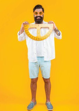 Geometri ölçer ile gülümseyen adamın fotoğrafı. Geometri açıölçeri olan adam sarıda izole edilmiş. Stüdyoda geometri açıölçeri olan bir adam var. Arka planda geometri iletkeni olan adam.