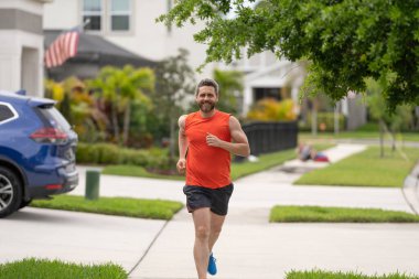 Koşan adam dışarıda koşma özgürlüğünden hoşlanır. Koşan adam koşarken mutluluk hisseder. Spor formundaki adam dışarıda koşuyor. Koşan adam mahallede yarışıyor. Etkin kal.