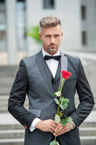 在特殊场合穿正装 有魅力的男人带着玫瑰迎接特殊的时刻 特定场合的室外燕尾服男 — 图库照片