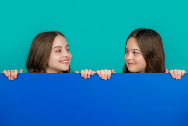 青い紙の後ろに広告のためのコピースペースを持つ笑顔の子供たち — ストック写真