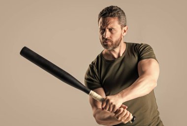 Stüdyoda sopayla dolaşan öfkeli bir suçlunun saldırganlığı. Sopayı tutan kızgın adamın fotoğrafı. Kızgın adam tehdit ediyor. Öfkeli adam öfkesini gri arka planda yalnız yarasayla ifade eder.