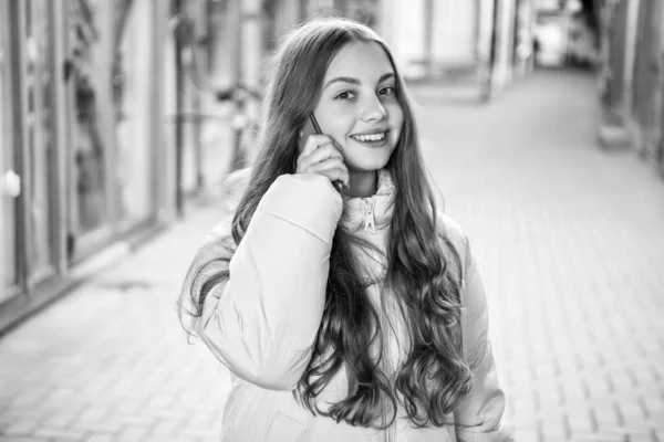 stock image photo of smiling teen girl having phone call outside. teen girl having phone call in the street. teen girl having phone call outdoor. teen girl having phone call conversation.