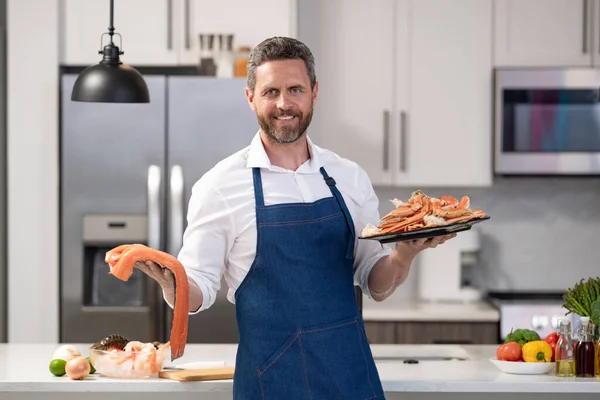 stock image positive chef cooking lobster and salmon seafood. chef with lobster and salmon seafood in the kitchen. photo of chef with lobster and salmon seafood. chef with lobster and salmon seafood.