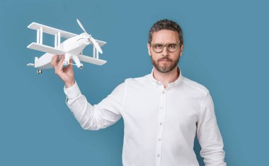 man launch aspirations isolated on blue background. man launch aspirations in studio. man launch aspirations with plane. photo of man launch aspirations with toy plane.