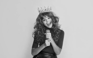 Sarı arka planda mikrofonu olan tacın içindeki pozitif çocuk.