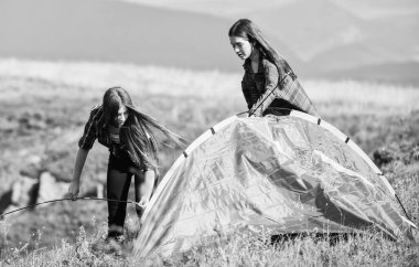 No care and no rush. mountain tourism camp. hiking outdoor adventure. family camping. reach destination place. two girls pitch tent. wanderlust discovery. friends spend free time together.