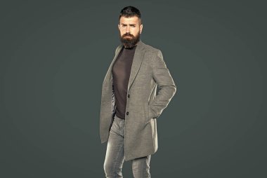 Kafkas sakallı olgun bir adam gri arka planda rahat giyinir..