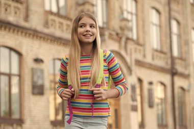 Gülümseyen liseli kızın fotoğrafı. Liseli kız. Sırt çantalı liseli kız. Açık havada okuyan genç kız..
