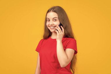 Sarı arka planda akıllı telefonu olan gülümseyen kız..