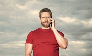 Adamın gökyüzü geçmişinde telefon konuşmaları var. Adam dışarıda telefonla konuşuyor. Adam telefonda konuşuyor, kırmızı tişört giyiyor. Bir adamın fotoğrafı telefonda konuşuluyor..