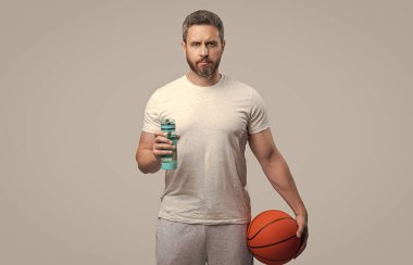 Sporcu basketbolcu adam su içmek için su tutuyor. Sporcu basketbolcu gri arka planda izole edilmiş. Stüdyoda sporcu basketbolcu. Sporcu basketbolcunun fotoğrafı..