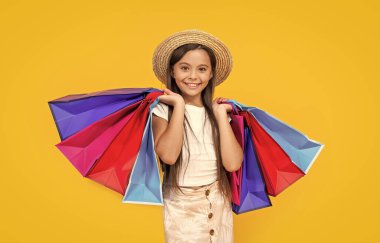 happy teen girl with shopping bags on yellow background.