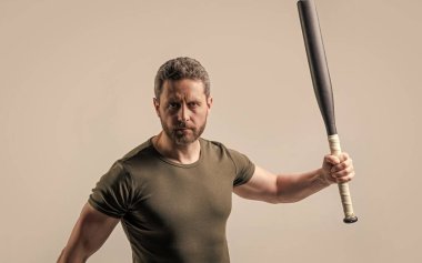 Adam gri arka planda kalan yarasalarla saldırganlığını ifade ediyor. Stüdyoda sopalı bir adamın saldırganlığı. Saldırgan bir adamın fotoğrafı. Saldırgan bir adam tehdit ediyor..