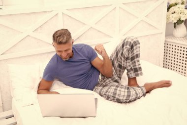 happy man freelancer at home in bedroom. photo of man freelancer at home with laptop. man freelancer at home. man freelancer at home in bed.