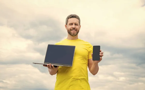 在天空背景下展示智能手机和笔记本电脑的人 — 图库照片