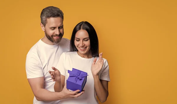 有礼物和广告的夫妇的照片 女人的一天 在黄色背景上孤立的一对惊奇的夫妇 在工作室里带着惊喜的一对夫妇 带惊喜礼物盒的度假夫妇 — 图库照片