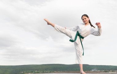 karate concept. teen girl practicing karate. girl karate fighter on sky background. copy space.