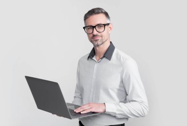 mature boss in eyeglasses working on computer on grey background.