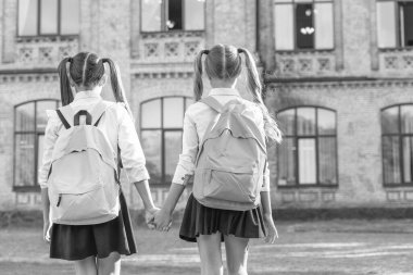 back view of two schoolkids with school backpack walking together outdoor. copy space.