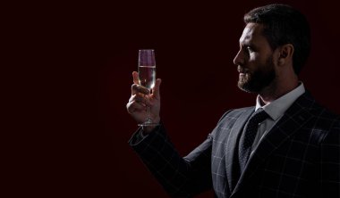 Stüdyoda tezahürat yapan şarap garsonu. Kırmızı arka planda şarap garsonu tezahüratı. Adam şarap garsonu tezahüratı, kopyalama alanı. Şarap garsonu şampanyayla tezahürat yapıyor..