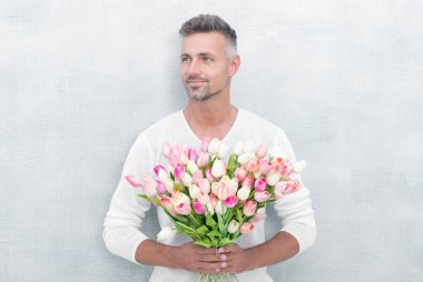 Mavi arka planda izole edilmiş sevgililer günü laleleri olan pozitif bir adam. Sevgililer Günü laleli bir adamın fotoğrafı. Sevgililer günü laleleri olan bir adam. Stüdyoda sevgililer günü laleleri olan bir adam..