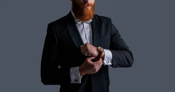 タキシードファッション 灰色の背景に隔離された腕時計でタキシードに身を包んだ髭の男のクロップドビュー タキシードと腕時計で撮影された男のスタジオ 上品な腕時計とタキシードを着た男が — ストック写真