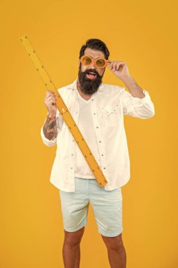 Okullu adamın cetvelle ölçülen fotoğrafı. Okullu adam ölçüsünde cetvel sarı üzerine izole edilmiş. Stüdyoda cetvelle ölçü almak. Arkaplanda cetvel olan okul adamı ölçüsü.