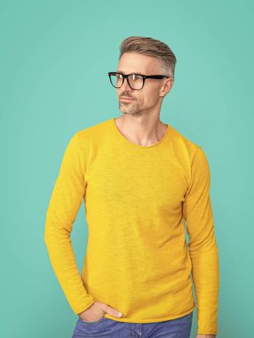 Yakışıklı bir adam mavi üzerine izole edilmiş göz giysisine bakar. Stüdyoda gözlüklerin içine bak. Dostum, arka plandaki göz takılarına bak. Gözlüklü bir adamın fotoğrafı..