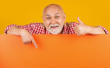 Boş afişlerde fotokopi alanı olan mutlu kıdemli adam. Reklam. işaret parmağı.