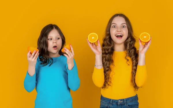 Έκπληκτος Έφηβες Κορίτσια Κατέχουν Πορτοκαλί Φρούτα Κίτρινο Φόντο — Φωτογραφία Αρχείου