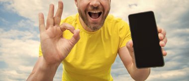 Akıllı telefon ekranı ile fotokopi alanı sunan adamın kırpılmış görüntüsü. Tamam.