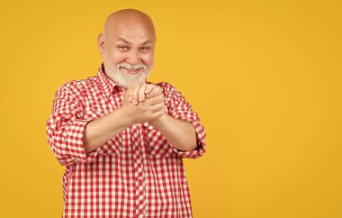 Sarı arka planda damalı gömlekli yaşlı adam ya da büyükbaba.