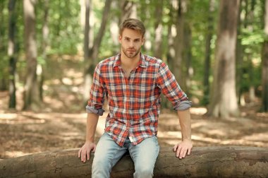 Kareli tişörtlü genç yakışıklı dışarıda oturuyor..