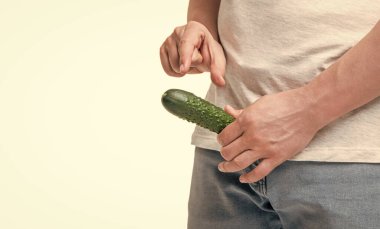 Man crop view showing small size gesture holding cucumber as penis at crotch level isolated on white, copy space.