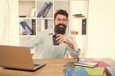 Ofis masasında oturup kahve içen mutlu bir işadamı..